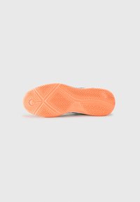 Shoe sole made of rubber, featuring a zigzag tread pattern in orange, with a smooth beige midsole and a white, textured upper edge.