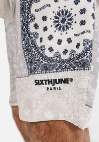 Shorts con un motivo paisley grigio e blu navy, con il logo nero "SIXTHJUNE PARIS". Realizzati in materiale leggero con una texture liscia.