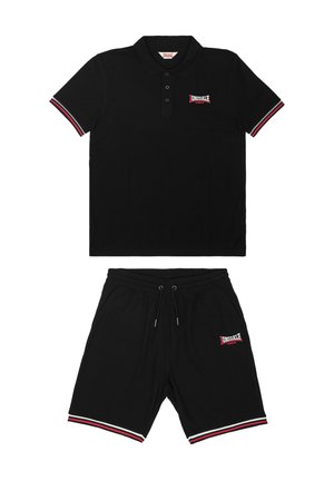 Ensemble polo noir et shorts avec poignets rayés rouges et blancs et logos "Lonsdale London" sur la poitrine et la jambe gauche.