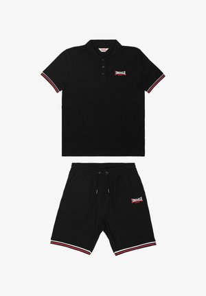 Set composto da polo nera e pantaloncini con polsini a righe rosse e bianche e loghi "Lonsdale London" sul petto e sulla gamba sinistra.