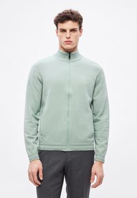 Πράσινο μπουφάν με φερμουάρ και ψηλό γιακά, υλικό με υφή και λογότυπο στο στήθος. Διαθέτει πλαϊνές τσέπες και ριμπ μανσέτες.