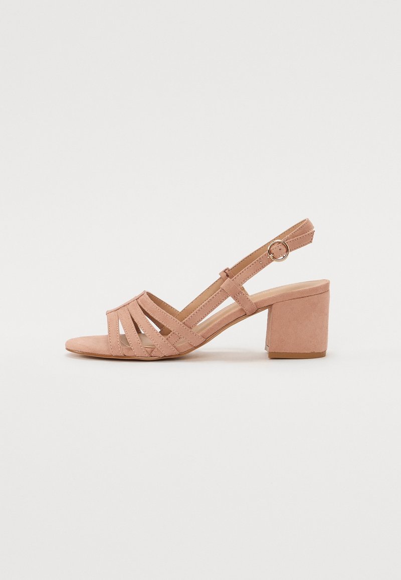 Sandale ouverte en daim rose avec talon bloc, multiples brides diagonales et bride de cheville réglable avec boucle dorée.