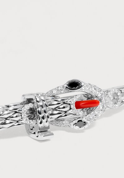 Fermoir de bracelet serpent en argent avec des yeux en pierres précieuses noires, des cristaux clairs et un détail de langue en corail rouge sur un bracelet en métal tressé.