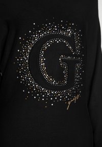 Schwarzer Sweatshirt mit einem großen strukturierten "G", umgeben von silbernen, goldenen und orangefarbenen Strasssteinen in einem funkelnden Muster.