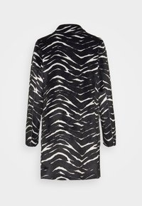 Schwarzer und weißer, zebra-musterter Mantel mit langen Ärmeln und klassischem Kragen, der eine weiche Textur und eine unstrukturierte Form aufweist.