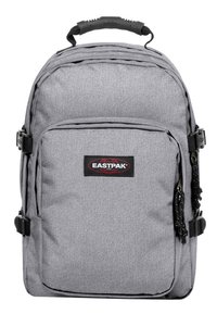 Mochila de tela gris con asa superior, bolsillo frontal, correas ajustables y parche del logo de Eastpak. Material texturizado con un diseño práctico.