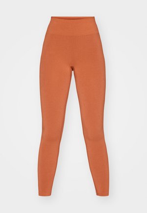 Orange High-Waist-Leggings aus weichem, dehnbarem Material. Glatte Textur mit einer figurbetonten Silhouette, nahtloser Verarbeitung und knöchellangem Design.
