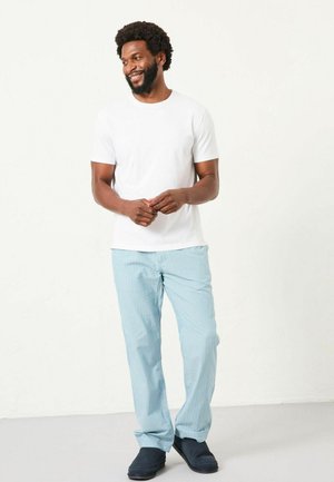 Weißes kurzärmliges T-Shirt, kombiniert mit hellblauen gestreiften Hosen und dunkelblauen Slippern. Glatter Stoff mit lockerer Passform.