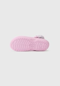 Rosa Crocs-Slipper von der Sohlenseite gezeigt, mit strukturiertem Grip und einem flauschigen Riemen über der Ferse auf einem schlichten Hintergrund.