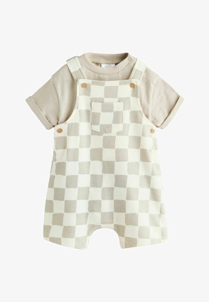 Beige kurzärmeliges Hemd kombiniert mit cremefarbenen und beigen karierten kurzen Overalls mit Fronttasche und Holzknöpfen.