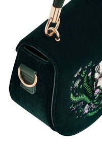 Ciemnozielona torebka z weluru w rogu z złotymi akcentami i haftem kwiatowym, przedstawiającym liście oraz małe kwiaty w odcieniach różu i zieleni.