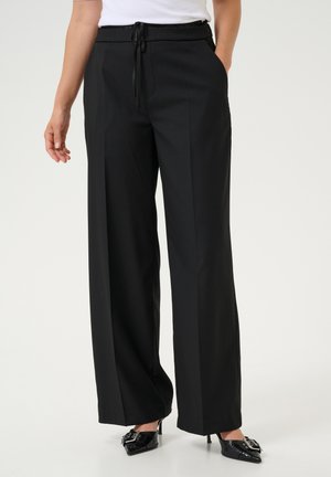 Black wide-leg trousers with a drawstring waistband, side pockets, and a smooth texture, paired with black pointed-toe heels.