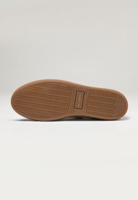 Suela de zapato de goma con un patrón de banda de rodadura ondulado. Color marrón con una etiqueta rectangular en relieve y el tamaño (42) impreso en ella. Textura suave.