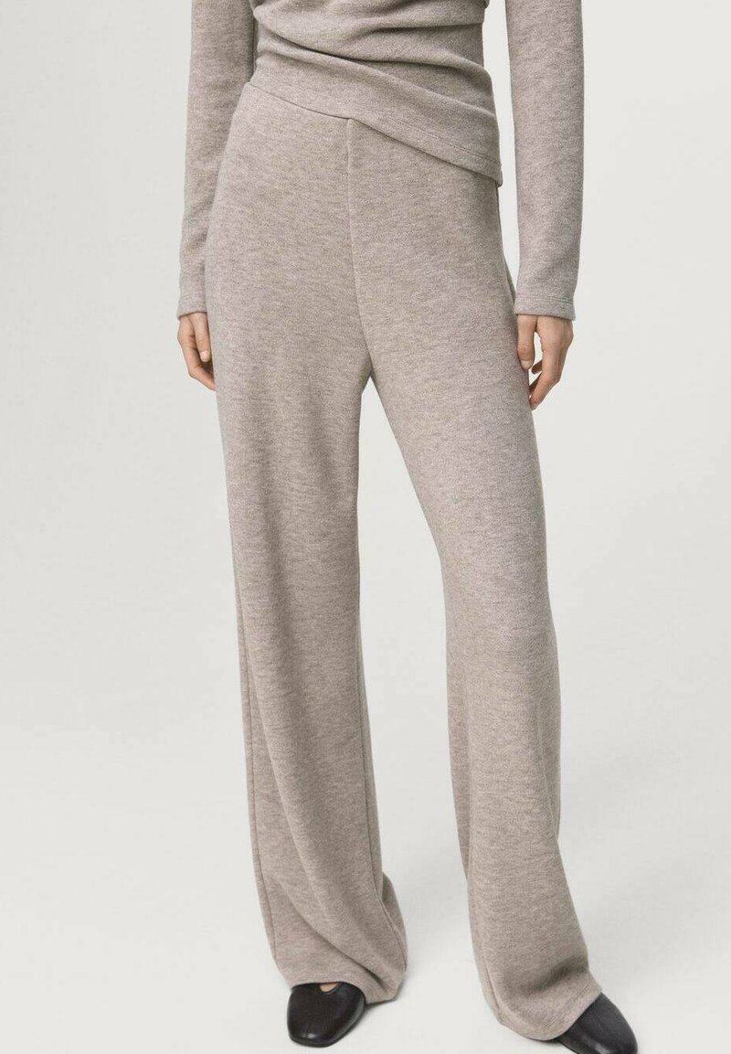 Beige gebreide wijde broek met een gladde textuur, voorzien van een taille met mid-rise en een vloeiende silhouet. Gecombineerd met een bijpassende top.