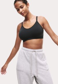 Svart sportbh i mjukt tyg med justerbara band och scallopad halsringning, kombinerad med grå sweatpants med sidofickor.