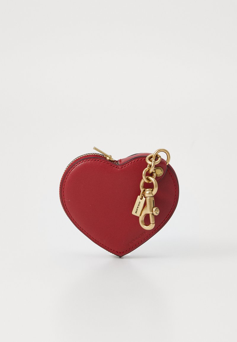 Red leather heart-shaped coin pouch with a gold zipper, gold keychain hardware, and a small lock detail. Smooth texture, compact design.