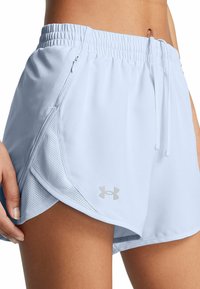Nahaufnahme einer Person, die hellblaue Sportshorts mit Netzseitenteilen, einem Reißverschlussfach, einem Kordelzugbund und einem Under Armour-Logo trägt.