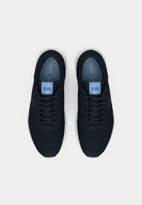 Paire de baskets noires Tommy Hilfiger avec tige en mesh, fermeture à lacets et semelles blanches, vues de dessus sur fond blanc.
