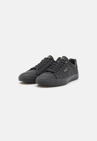 Sapatilhas de couro preto com atacadores planos, uma superfície texturizada, suporte almofadado para o tornozelo e discretos detalhes em dourado no lado exterior.