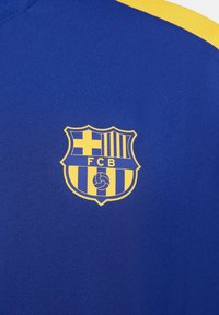 Tejido azul con un escudo del FC Barcelona en acentos amarillos, de forma de escudo, con una cruz, rayas verticales y un detalle de balón de futbol.