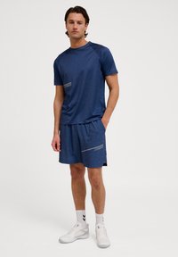 Conjunto desportivo composto por uma camisa azul marinho de manga curta e calções combinando com um padrão geométrico. Feito de tecido leve e respirável.