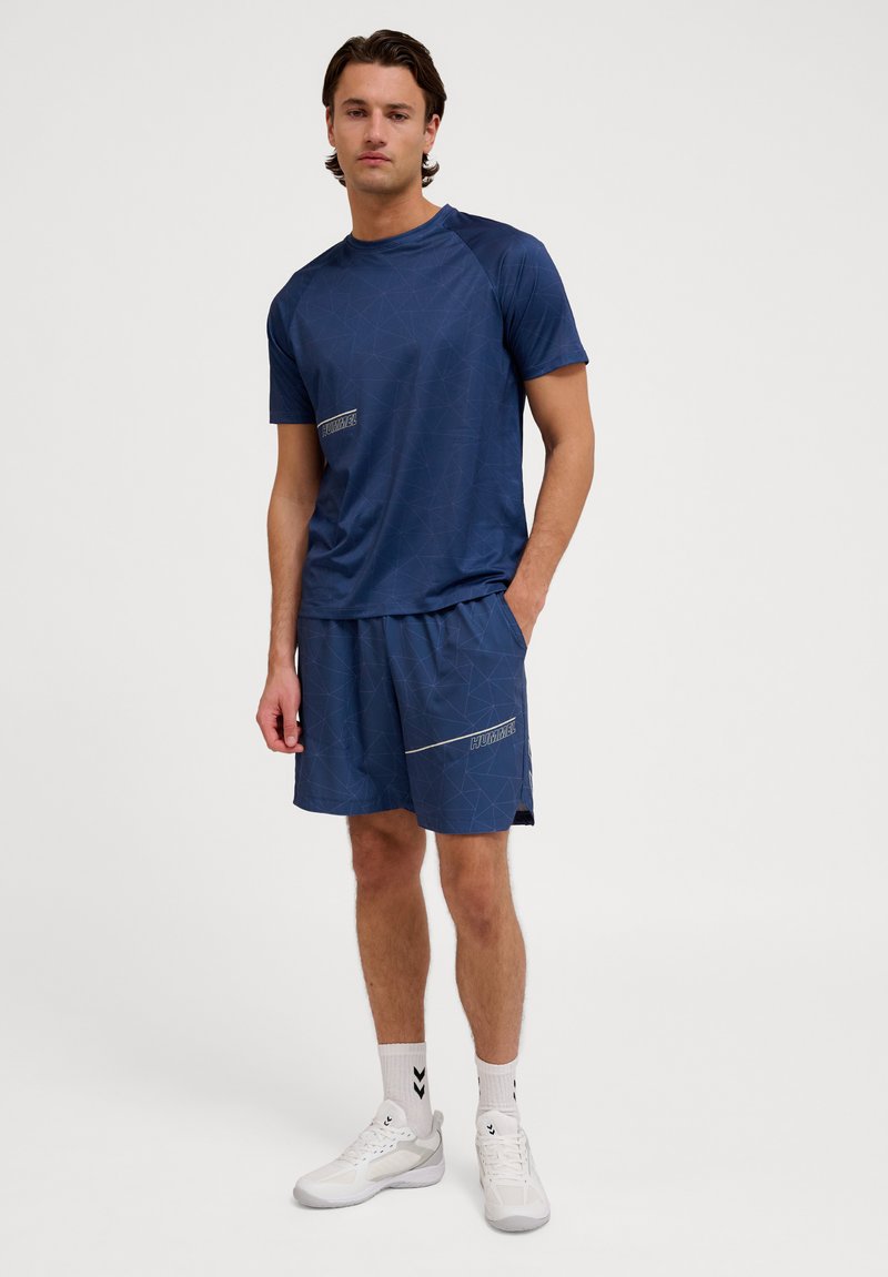 Conjunto desportivo composto por uma camisa azul marinho de manga curta e calções combinando com um padrão geométrico. Feito de tecido leve e respirável.