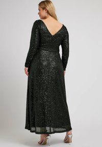 Vestido negro con lentejuelas con diseño de espalda en V, mangas largas y falda de largo completo, que presenta una textura brillante y un brillo sutil.