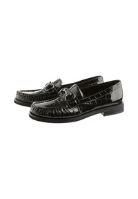 Mocassins en cuir verni noir avec une texture croco, dotés de garnitures décoratives et d'une semelle basse et plate. Coutures détaillées à l'avant.