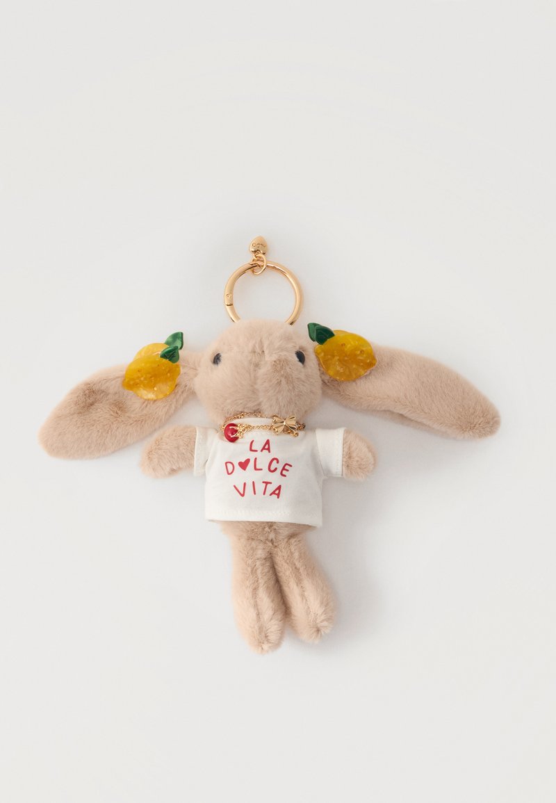 Blød beige kanin-nøglering iført hvid "La Dolce Vita" t-shirt med gule frugtdekorationer på ørerne og en guldring som vedhæng.