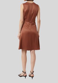Braunes Satin-Ärmelloses Kleid mit schwingendem Saum, Rückenzipper, glatter Textur und A-Linie Silhouette. Kombiniert mit schwarzen Riemchensandalen.