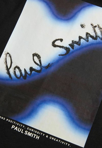 Melnā T-kreklā ar grafisko dizainu. Centrāls balts taisnstūris ar zilu gradienta kontūru. Melnā rokrakstā ir teksts "Paul Smith."