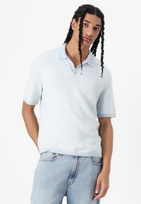 Ανοιχτό μπλε polo πουκάμισο κοντό μανίκι με υφή διαμαντιού, αντίθετο γιακά και ριγωτούς καρπούς που φοριέται με ανοιχτόχρωμα τζιν.