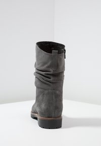 Botte cheville en daim gris au design décontracté, présentant une fermeture éclair et une semelle en caoutchouc texturé. L'intérieur est doté d'un revêtement doux.