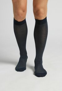 Mörkblå knälånga strumpor med ribbad struktur och släta manschetter, som har en jämn yta och en åtsittande design runt vaden.