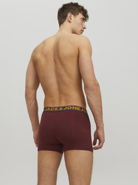 Bordeauxfarbene Boxershorts mit einem elastischen Bund in Schwarz und Orange, der das Logo "JACK & JONES" trägt. Glatte Stoffqualität und taillierter Schnitt.
