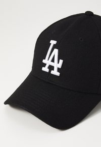 Sort baseball cap lavet af blødt stof med en buet skygge, der har et hvidt broderet "LA" logo foran.