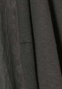 Donkergrijze stof met verschillende texturen; bevat gladde en ribbelige delen, wat een subtiele wisselwerking van licht en schaduw benadrukt.