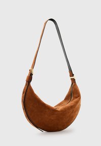 Borsa a spalla in suede marrone con forma a mezzaluna, tracolla in pelle nera e dettagli in metallo dorato; presenta una chiusura con zip e dettagli cuciti.