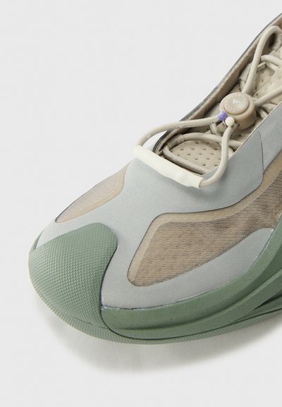 Lace-up sneaker with a grey and green design, featuring mesh panels, textured rubber sole, and a distinctive shape with rounded accents.