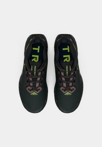 Black athletic shoes with a textured upper, featuring a green and gray pattern, padded tongue, and reflective accents. Laces in dark tones.
