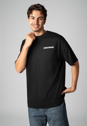 Schwarzes Baumwoll-T-Shirt mit kurzen Ärmeln und Rundhalsausschnitt, mit weißem Schriftzug "WORLDWIDE" auf der linken Brustpartie. Legere Passform, glatte Textur.
