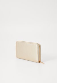Portafoglio in pelle dorata con superficie texturizzata, chiusura a zip e zip pull lucido dorato. Forma rettangolare compatta.
