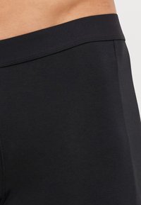Fekete, testre simuló leggings sima textúrával és széles rugalmas derékkal, lapos varratokkal a kényelem és tartósság érdekében.