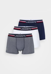 Drei Paare Herren-Boxershorts: eine in Marineblau, eine in Weiß und eine graue mit dünnen Streifen. Alle verfügen über einen elastischen Taillenbund mit Markenlogo.