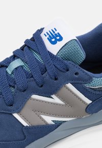 Blå mocka och nät sneakers med grå accenter, framträdande "N"-logotyp och texturerade snören. Har en vadderad tunga och mjukt inre.