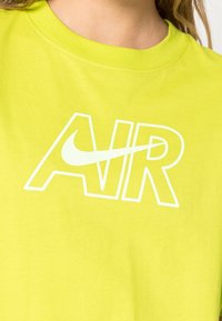 Ljusgul bomullströja med stor vit "AIR"-text och en Nike-logotyp i mitten. Slätt material och klassisk rund halsringning.