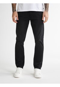 Zwarte denim jeans met een slim fit, met een gladde textuur, minimale stiksels en een klassiek vijf-pocket ontwerp, gecombineerd met witte sneakers.
