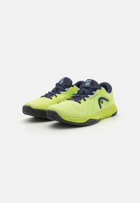 Neon gule joggesko med mesh-overdel, marineblå detaljer og strukturert svart såle. Har forsterket tå og flate lisser.