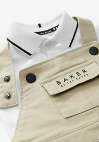 Beige haalit mustilla napeilla, hopeisilla yksityiskohdilla ja valkoisella kauluspaita, jossa on musta raita. Etiketissä lukee "BAKER by TED BAKER."