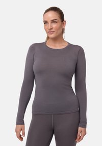 Langærmet top i blødt, gråt stof med rund halsudskæring. Tætsiddende design, glat tekstur og subtil sømdetaljering langs ærmerne.